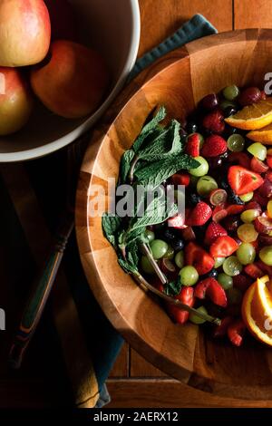 flat lay of fruit inside a wood bowl with apples on a kitchen table Stock Photo