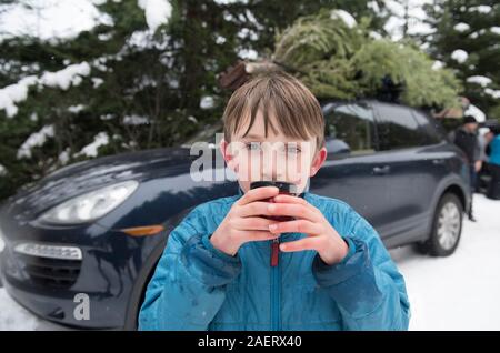 A boy drinks hot chocolate after getting a Christmas tree. Stock Photo