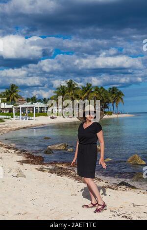Older woman posing on a beach with a black dress on the Mayan Riviera of Mexico near Tulum Stock Photo