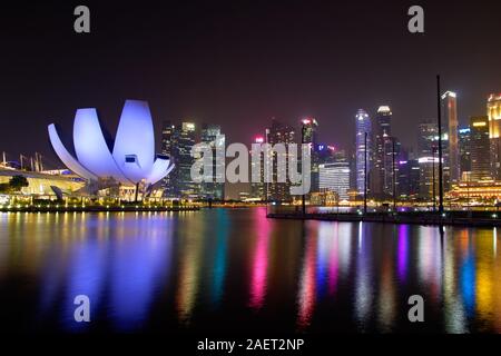 Panorama of Marina Bay water reflection colours at night, with viewpoint lotos flower shape building and skyscrapers in background