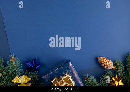 Christmas composition with decorations, gift boxes baubles and branches of fir tree on classic blue background. Christmas holidays background with cop Stock Photo