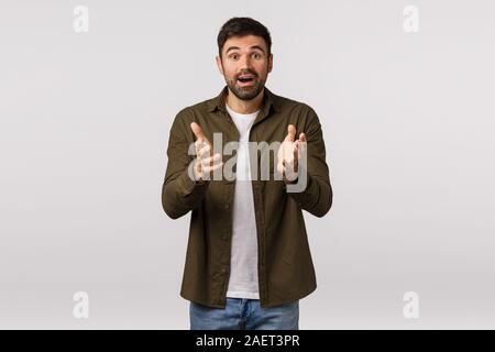 Cheerful and relieved happy surprised young kind bearded man, describe his impressions and amazement, gesturing with hands as having conversation Stock Photo