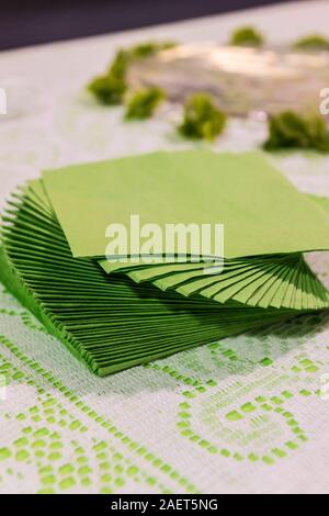 Some green / sage colored napkins twist piled on a table with lace table cloth. Stock Photo