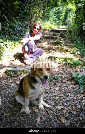 woman sitting on the steps of a path with her beagle dog in the foreground Stock Photo