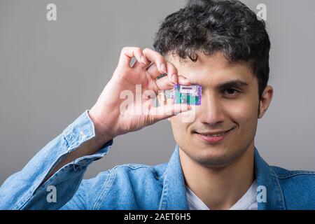 Young man holding a USB connectivity for standard SD memory cards with  right hand in front of his face Stock Photo