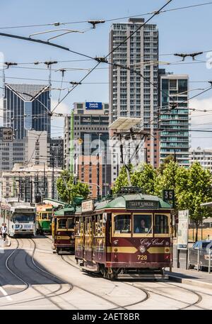 Melbourne, Australia - November 16, 2009: Cityscape with tall buildings and street scene with succession of trams at stop with traffic lights and peop Stock Photo