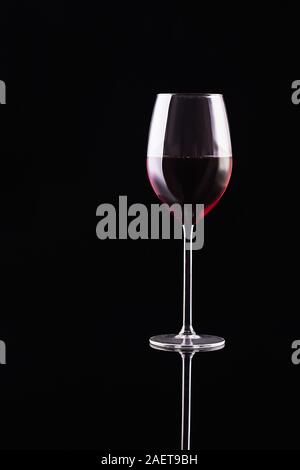 Glass of red wine on black background. Aromatic wine. Strict style. Wine on the dark