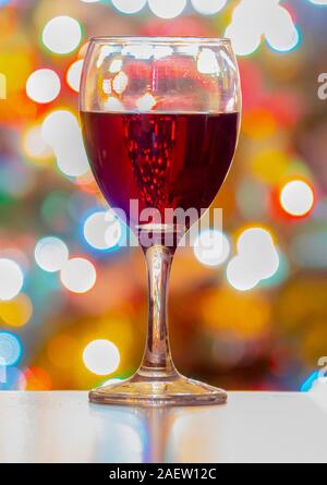 A Cup of wine with Christmas lights on the Background. Vertical view Stock Photo