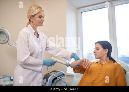 Blond doctor in sterile gloves working with patient Stock Photo