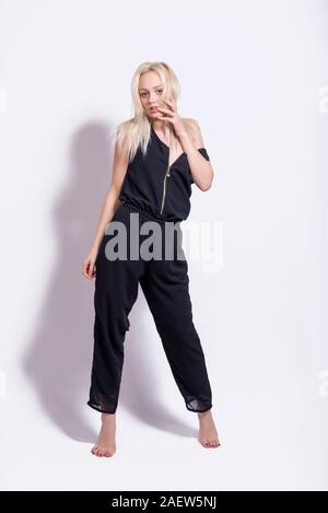 young woman in black overalls fun posing on gray background Stock Photo