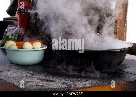 Preparation of shurpa in a cauldron on a Russian stove on an open fire Stock Photo