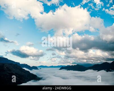 Bed of fog and clouds between the mountain valley in Sapa, Vietnam. Mountains among the clouds. Beautiful landscape with high mountains, blue sky and Stock Photo