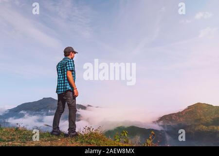 Young traveler standing and looking at view of nature in Sapa, Vietnam in rainy season. man in the mountains looking into the distance Stock Photo