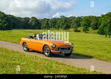 1974 70s yellow orange MG B MGB; Classic cars, historics, cherished, old timers, collectable restored vintage veteran, collector vehicles of yesteryear arriving for the Mark Woodward motoring event at Leighton Hall, Carnforth, UK Stock Photo