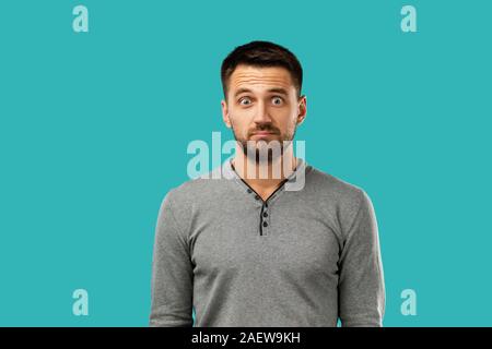 Portrait of young frowned handsome bearded man on blue background. facial expression Stock Photo