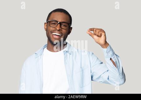 Happy excited millennial african american guy showing small prices gesture. Stock Photo