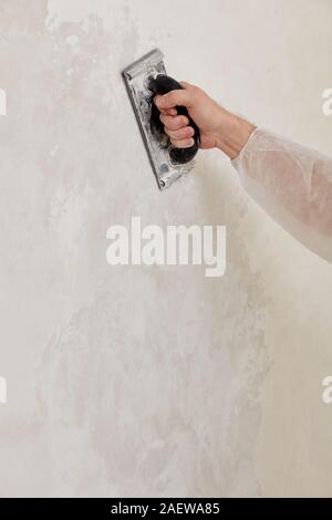 Hand of a man sanding a wall after plastering Stock Photo