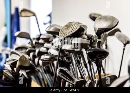 Golf caddy room storage room with sets of poles irons. Sets of golf clubs and equipment in storage space. Stock Photo