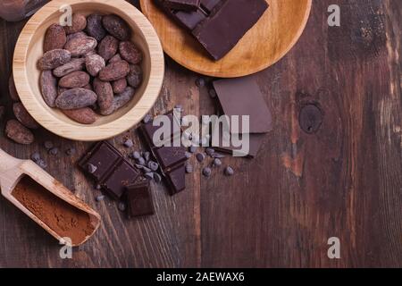 Cocoa beans and powder and chocolate bar pieces on wooden background Stock Photo