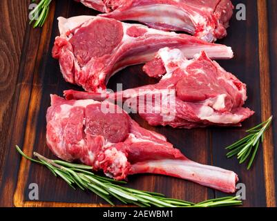 Raw lamb cutlets on bone on a dark brown wooden background, lamb ribs, side view. Stock Photo