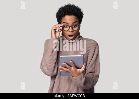 Surprised millennial affrican american woman looking at digital tablet screen. Stock Photo