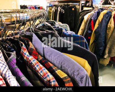 Used clothes on hangers in second hand Stock Photo