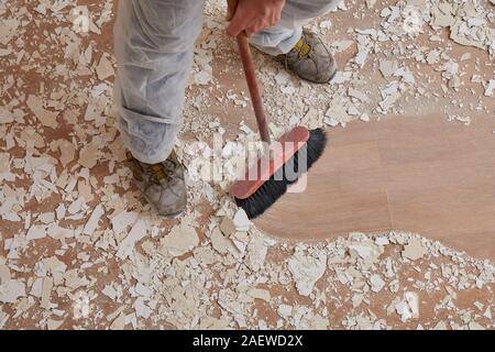 Builder sweeping the floor after renovation Stock Photo