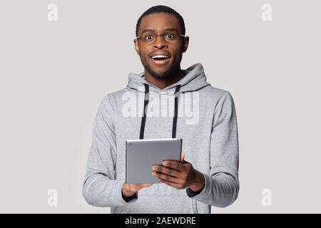 Surprised black young guy in eyeglasses holding digital tablet. Stock Photo