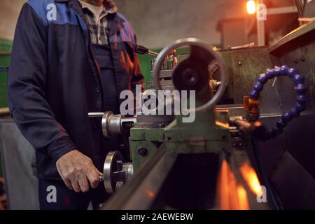 Close-up of manual worker in special clothing working on lathe in the plant Stock Photo