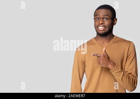 Worried african american guy, pointing aside at blank copy space. Stock Photo
