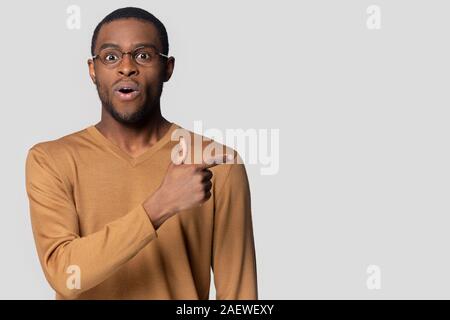 Surprised black guy pointing finger aside on empty copy space. Stock Photo