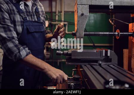 Close-up of operator in work wear operating on the machine in the factory Stock Photo