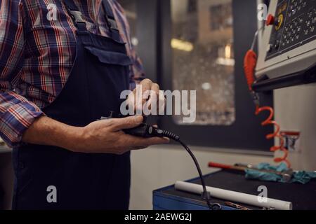 Mature manual worker holding control panel and controlling the work of machine Stock Photo