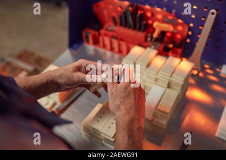 Close-up of man holding wood details and making the hole with work tool during his work in the workshop Stock Photo