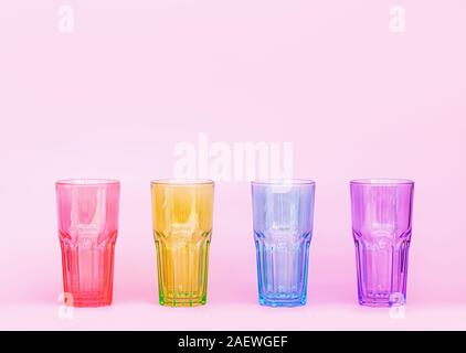 Multi-colored glasses for drinks on a pink background. Glasses of glass. Minimastic composition. Close up. Stock Photo
