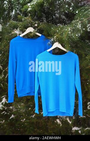 Clothes on hangers in the colors of the year 2020. Classic blue color of the year 2020. Sweaters, sweatshirts in classic blue color. Stock Photo