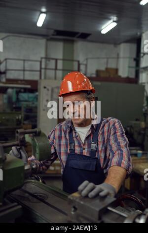 Serious mature worker concentrating on his work at lathe he cutting metal Stock Photo