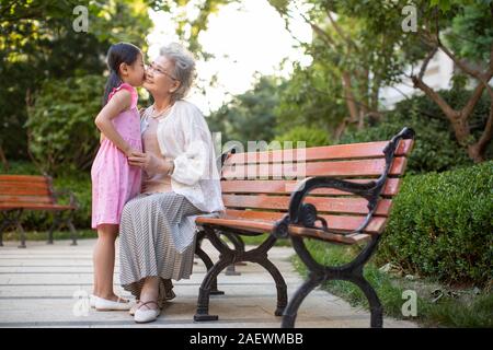 Happy little girl kissing her grandmother in park Stock Photo