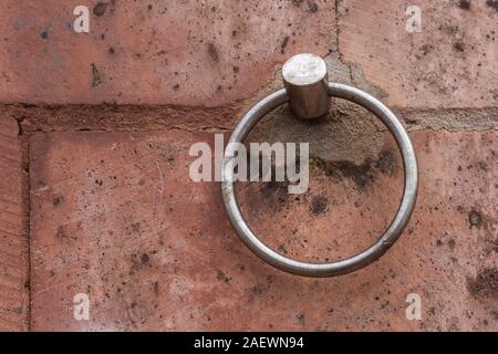 Orange-red color of the wall made of bricks. Round steel walled up holder. Bosa, Sardinia, Italy. Stock Photo