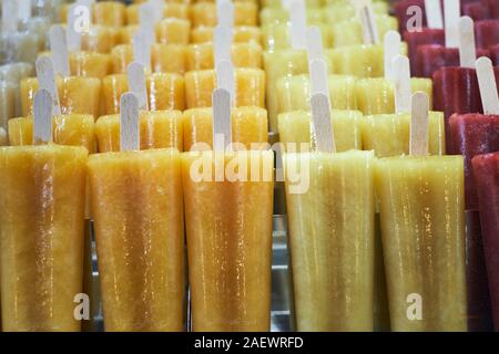 Fresh natural pure fruit juice flavoured ice lollies on wooden sticks for sale in a freezer counter - ice cream - ice popsicles - ice pops - flavours Stock Photo