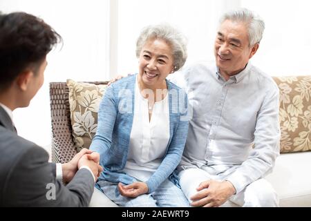 Happy senior couple shaking hands with financial advisor Stock Photo