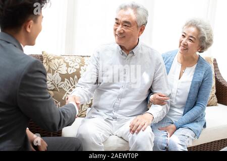 Happy senior couple shaking hands with financial advisor Stock Photo
