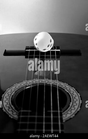 Eggshell lies on the guitar bridge with reflection in the guitar choir pus in black and white Stock Photo
