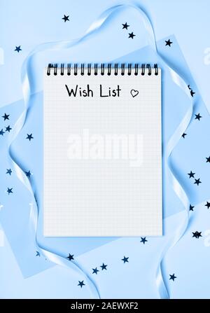 Notepad for wish list on a blue background with stars. Concept of New Year or holiday dreams. Flat lay. Stock Photo