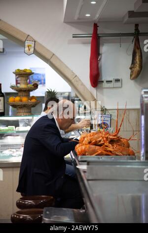 Man eating at Counter at 'O Cacho Dourado' Restauarnt in Lisbon, Portugal Stock Photo