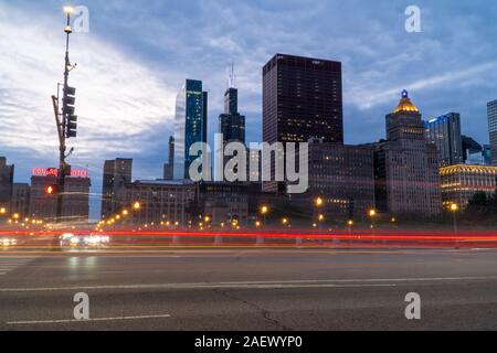 Chicago, IL - Circa 2019: Night time establishing shot of downtown Chicago skyline long exposure light trails of cars passing through busy intersectio Stock Photo