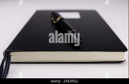 A black pen on top of a closed black notebook Stock Photo