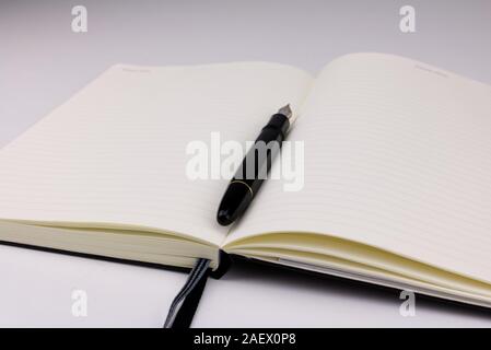 A black fountain pen on top of an open blank notebook Stock Photo