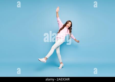 Full length body size turned photo of positive pink cheerful ecstatic overjoyed preteen balancing to prevent falling curly wavy isolated blue pastel Stock Photo