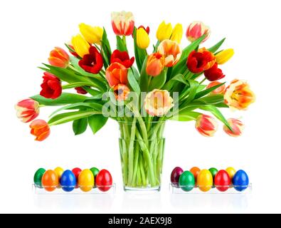 Gorgeous colorful bouquet of tulips in a glass vase, with Easter eggs on both sides, isolated on white Stock Photo